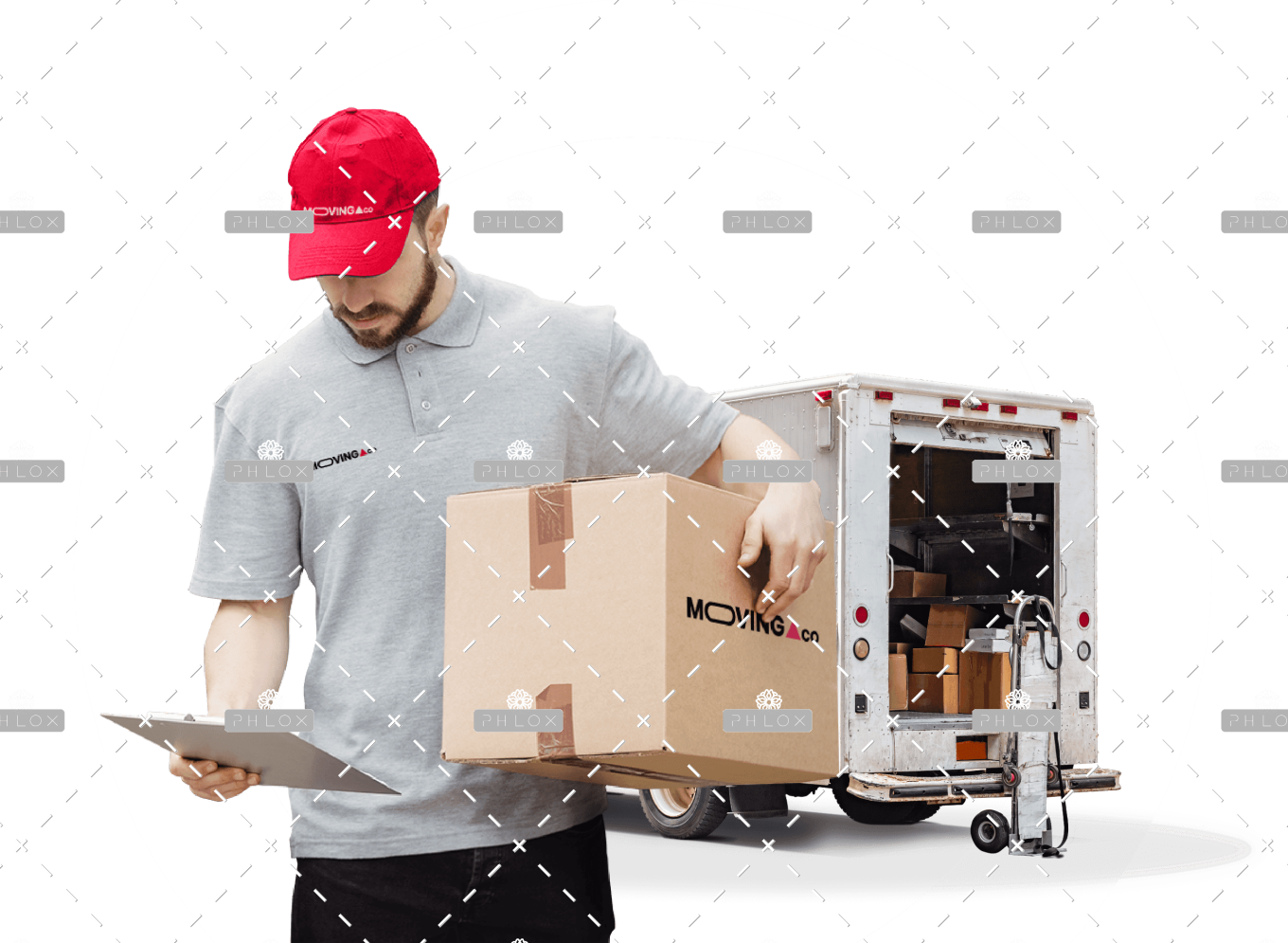Delivery worker in a gray polo and red cap carries a large cardboard box toward a moving truck in the background.